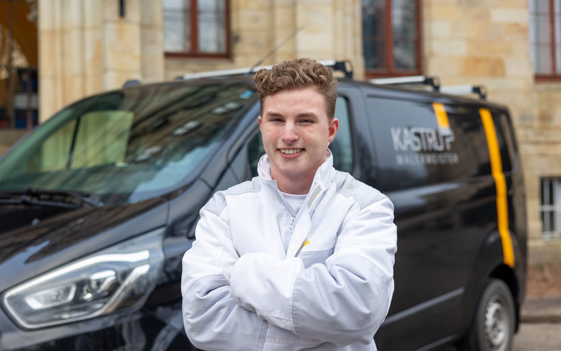 Ein Mann steht mit verschränkten Armen vor einem Lieferwagen.