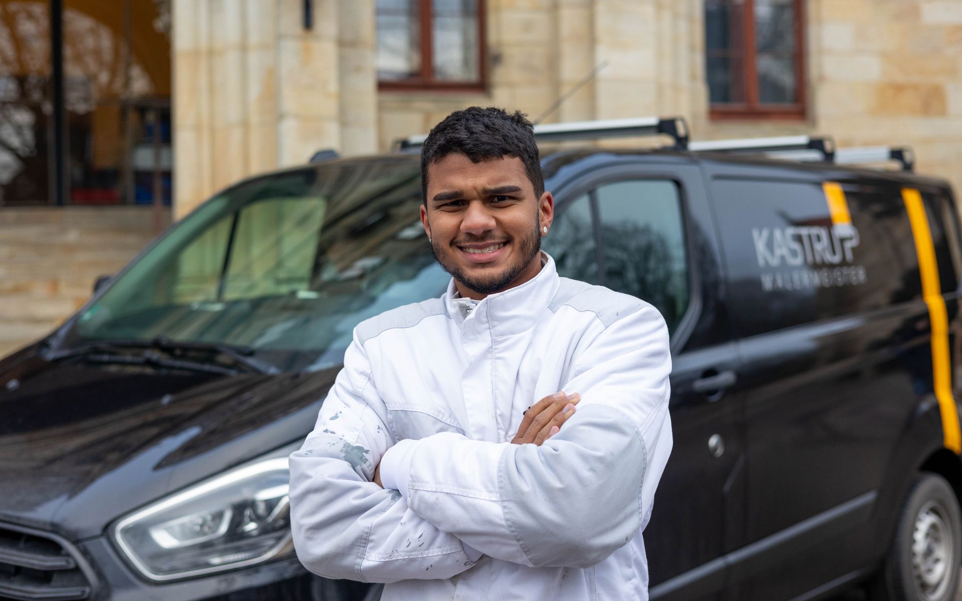 Ein Mann steht mit verschränkten Armen vor einem Lieferwagen.