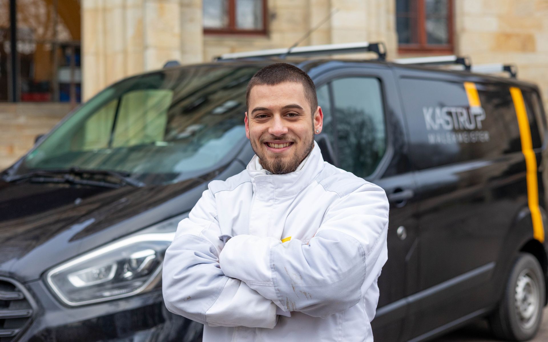 Ein Mann steht mit verschränkten Armen vor einem schwarzen Lieferwagen.