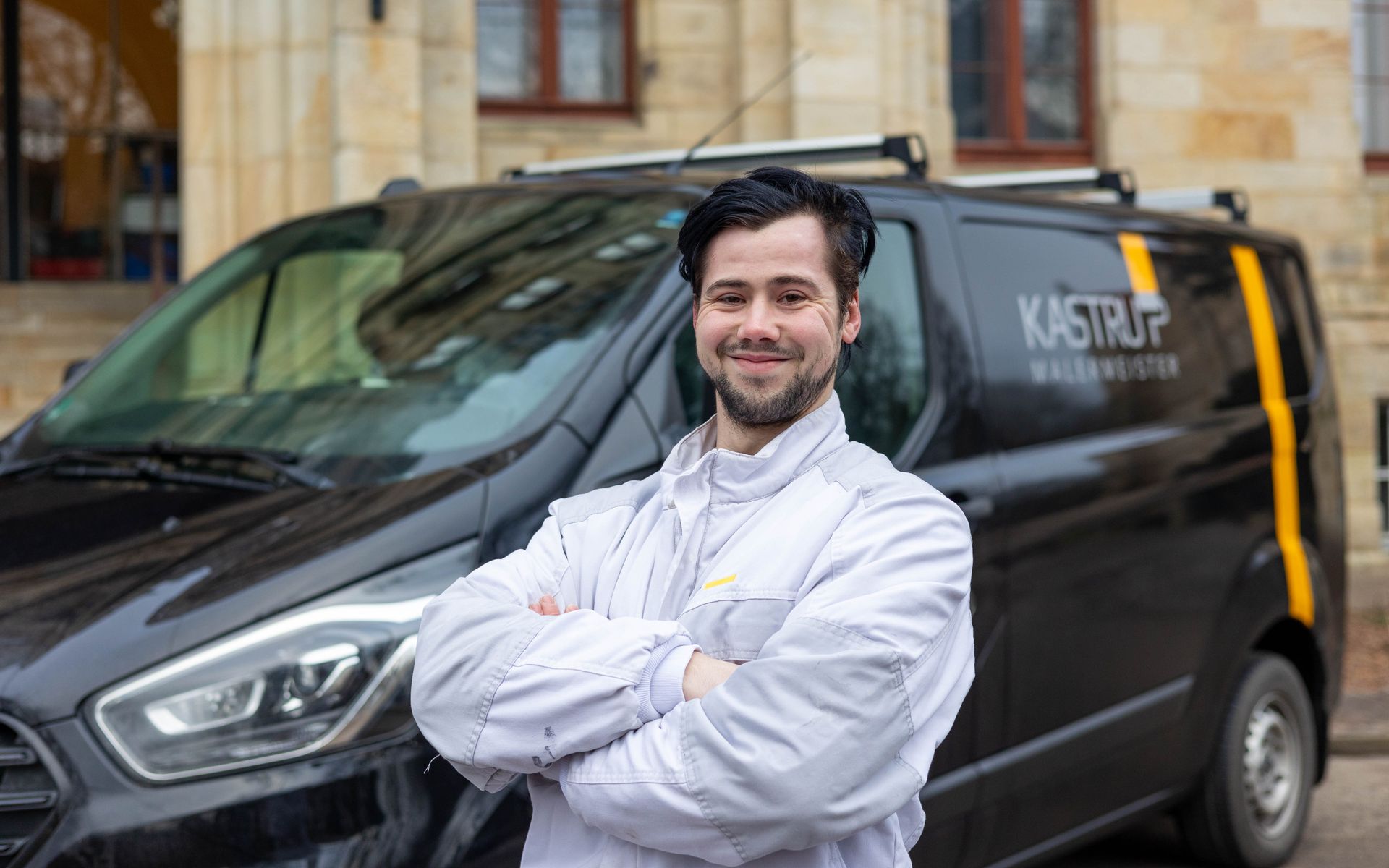 Ein Mann steht mit verschränkten Armen vor einem Lieferwagen.