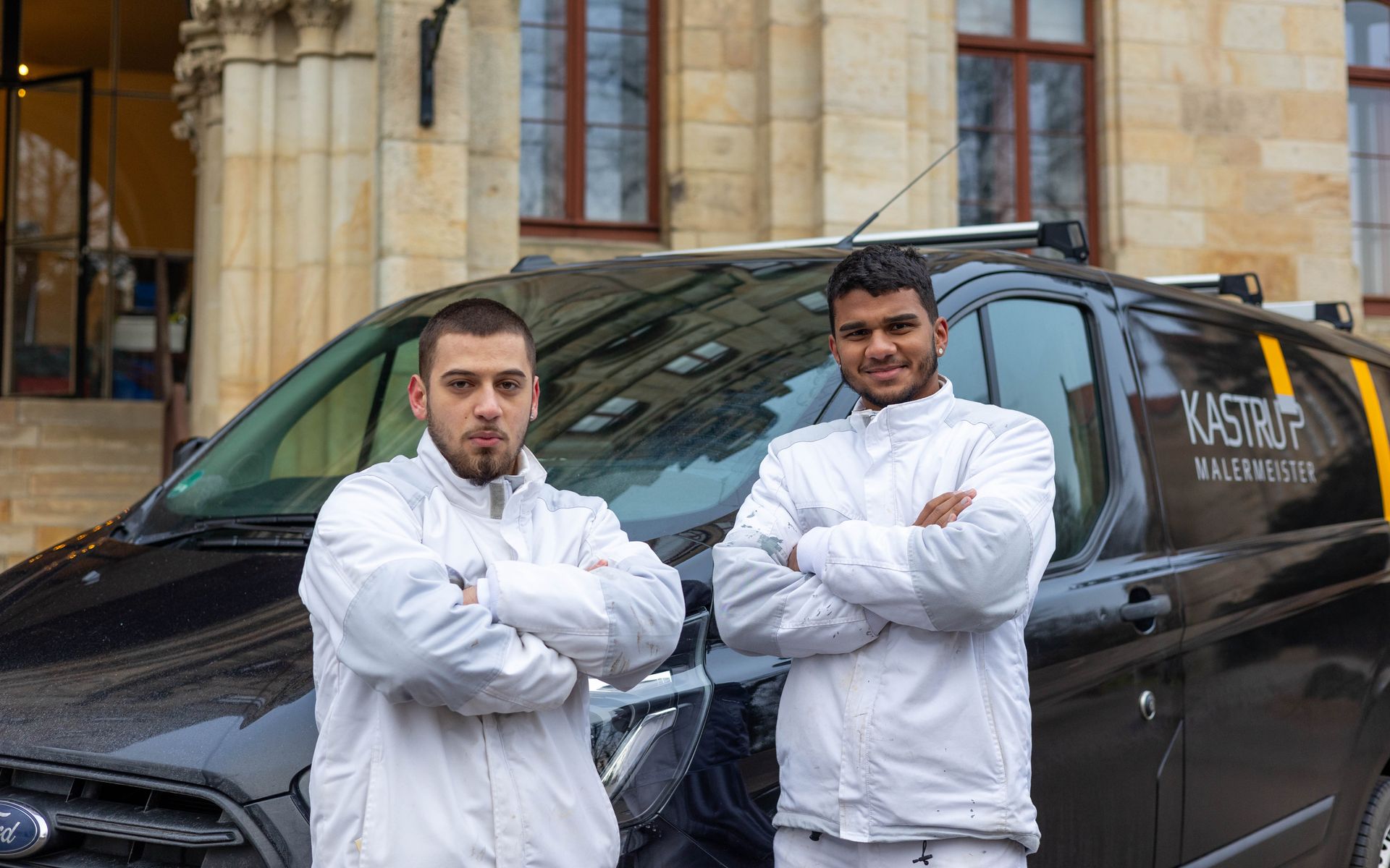 Zwei Männer stehen mit verschränkten Armen vor einem Lieferwagen.