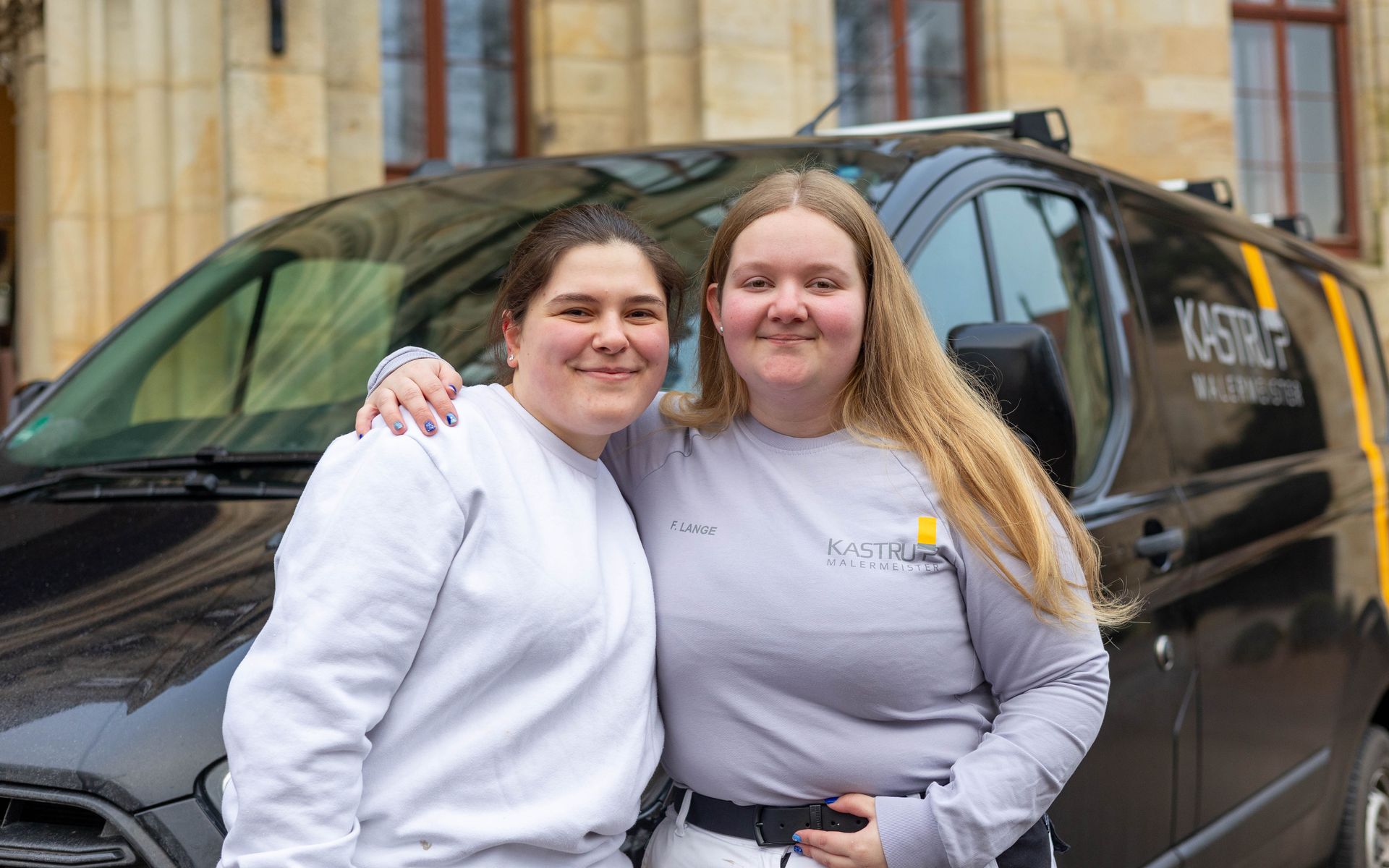 Zwei Frauen posieren vor einem Lieferwagen für ein Foto.
