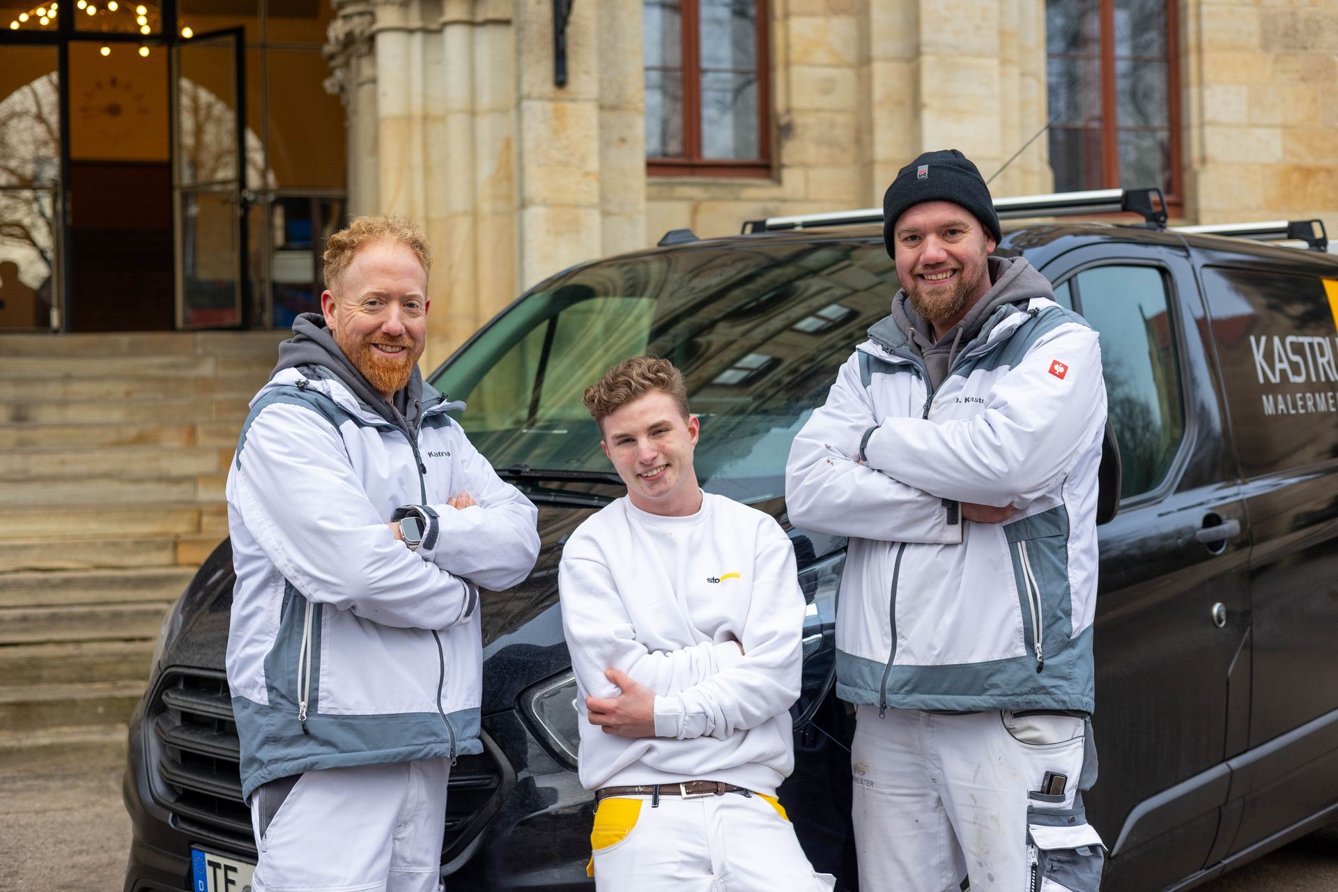 Drei Männer posieren vor einem Lieferwagen für ein Foto.