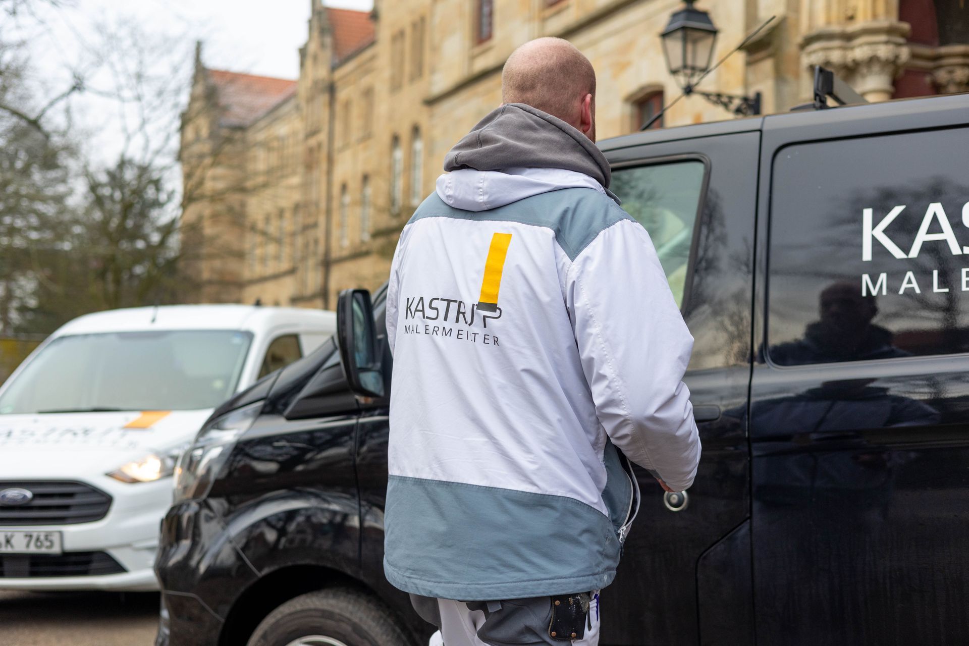 Ein Mann steht vor einem schwarzen Lieferwagen.