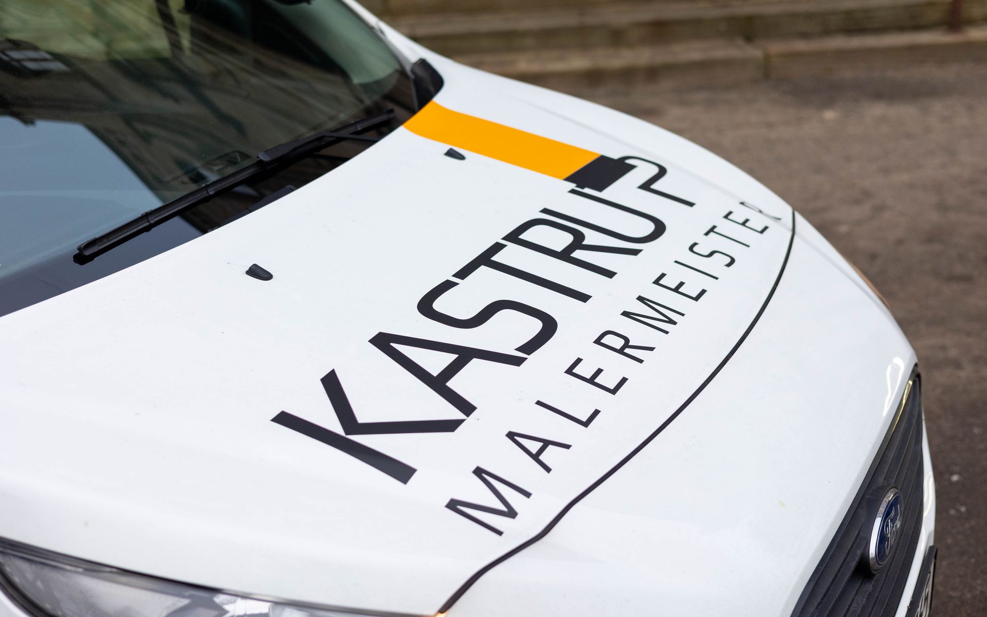 Ein weißer Lieferwagen mit dem Wort Kastrup Malermeister auf der Motorhaube