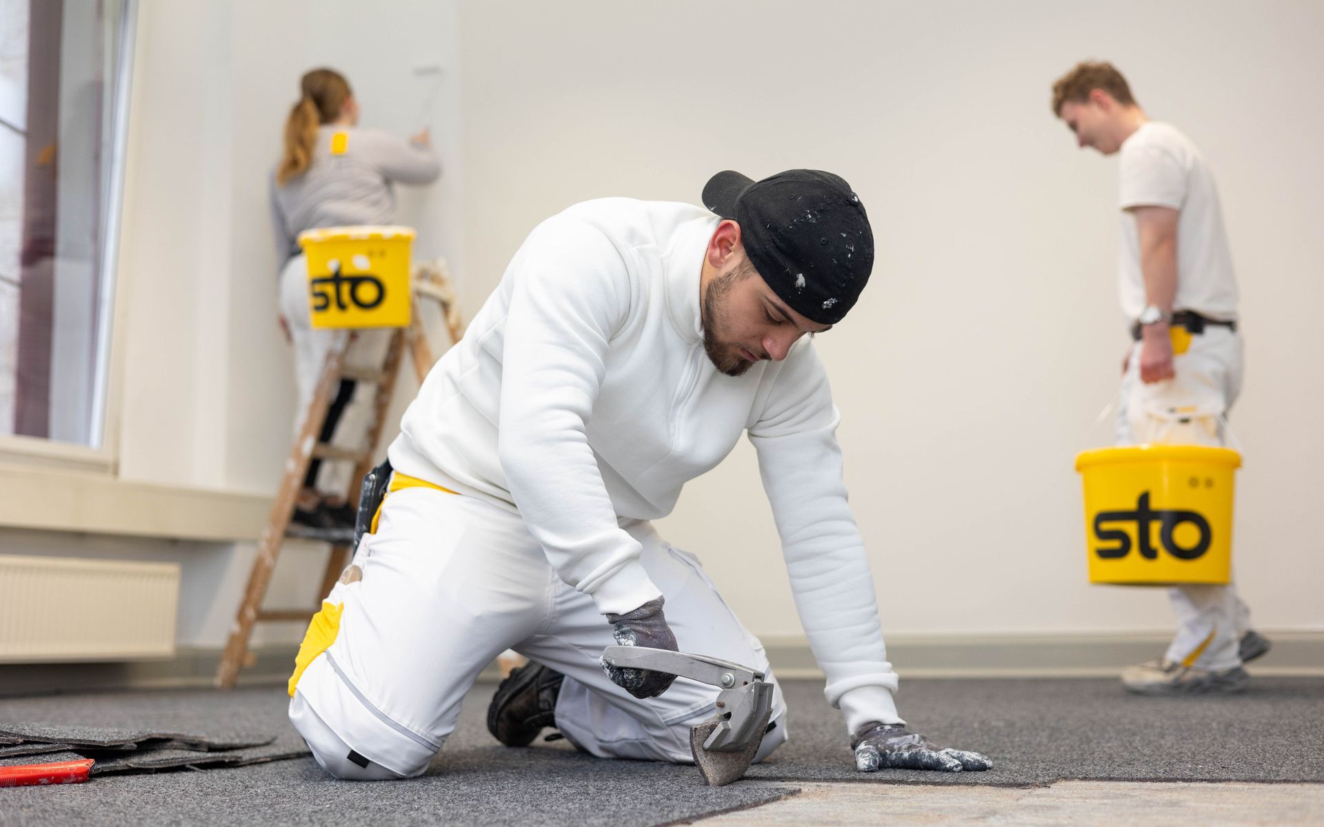 Ein Mann kniet mit einem Hammer in der Hand auf dem Boden.