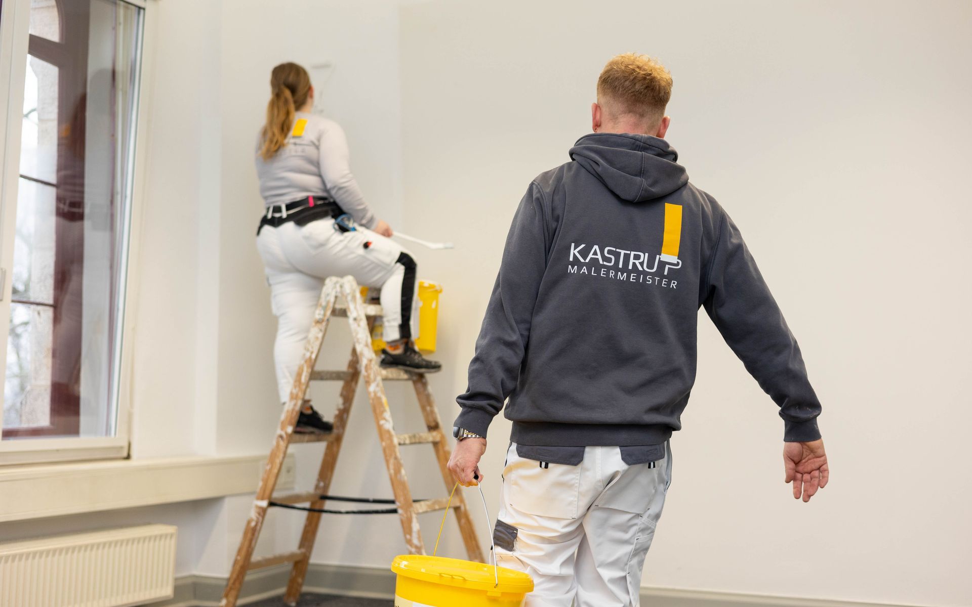 Ein Mann und eine Frau streichen eine Wand in einem Zimmer.