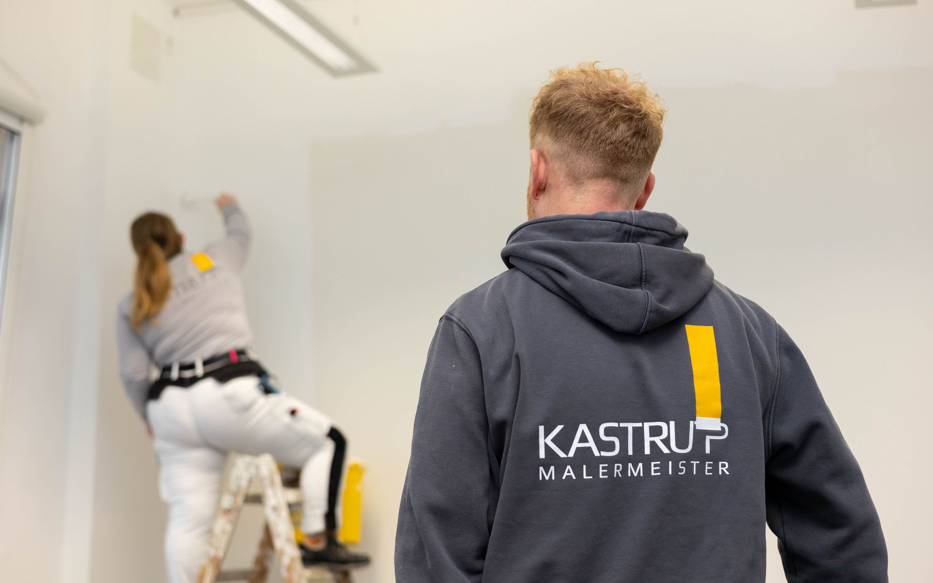 Ein Mann steht vor einer Frau und streicht eine Wand.