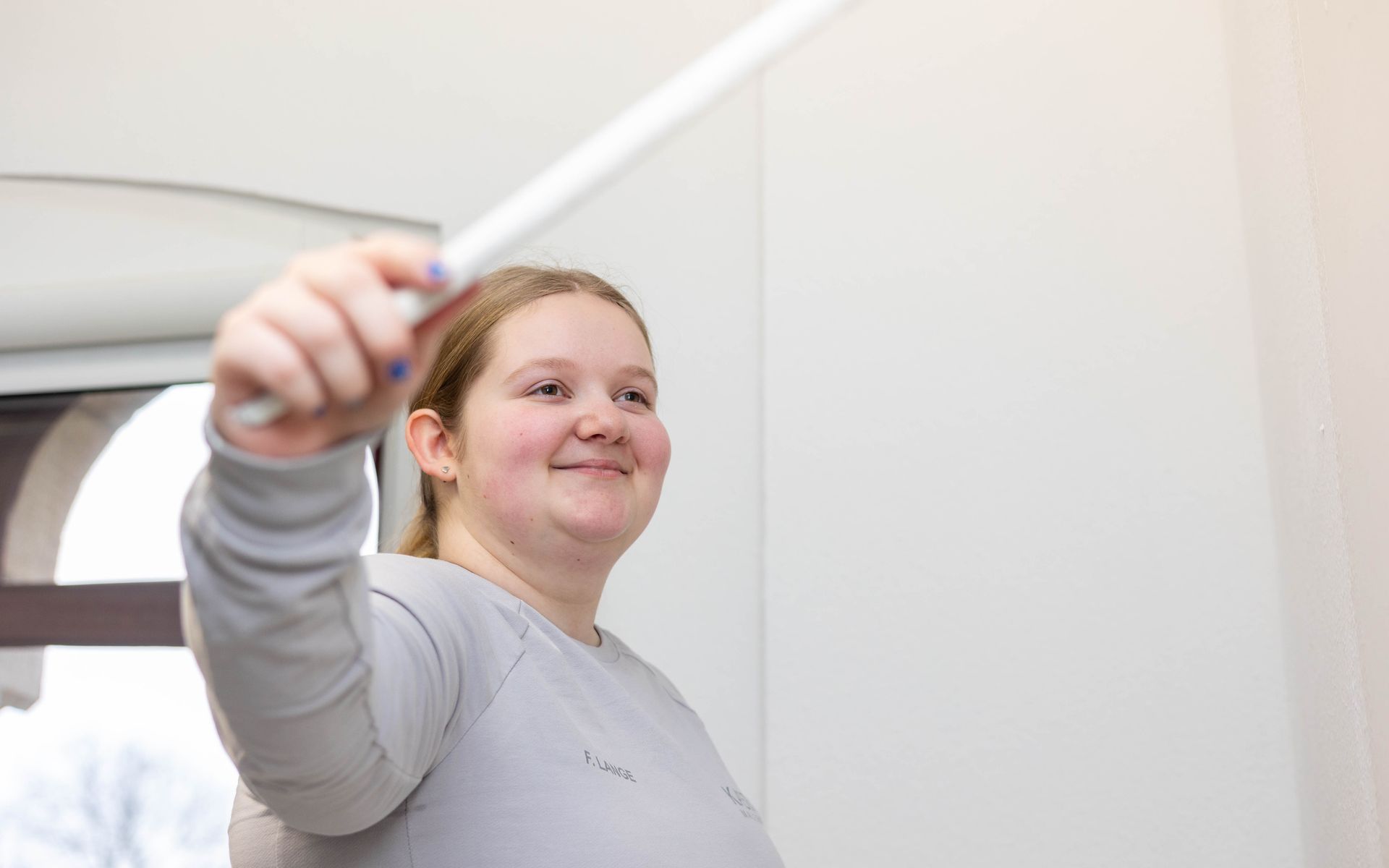 Eine junge Frau hält einen weißen Stock in der Hand.
