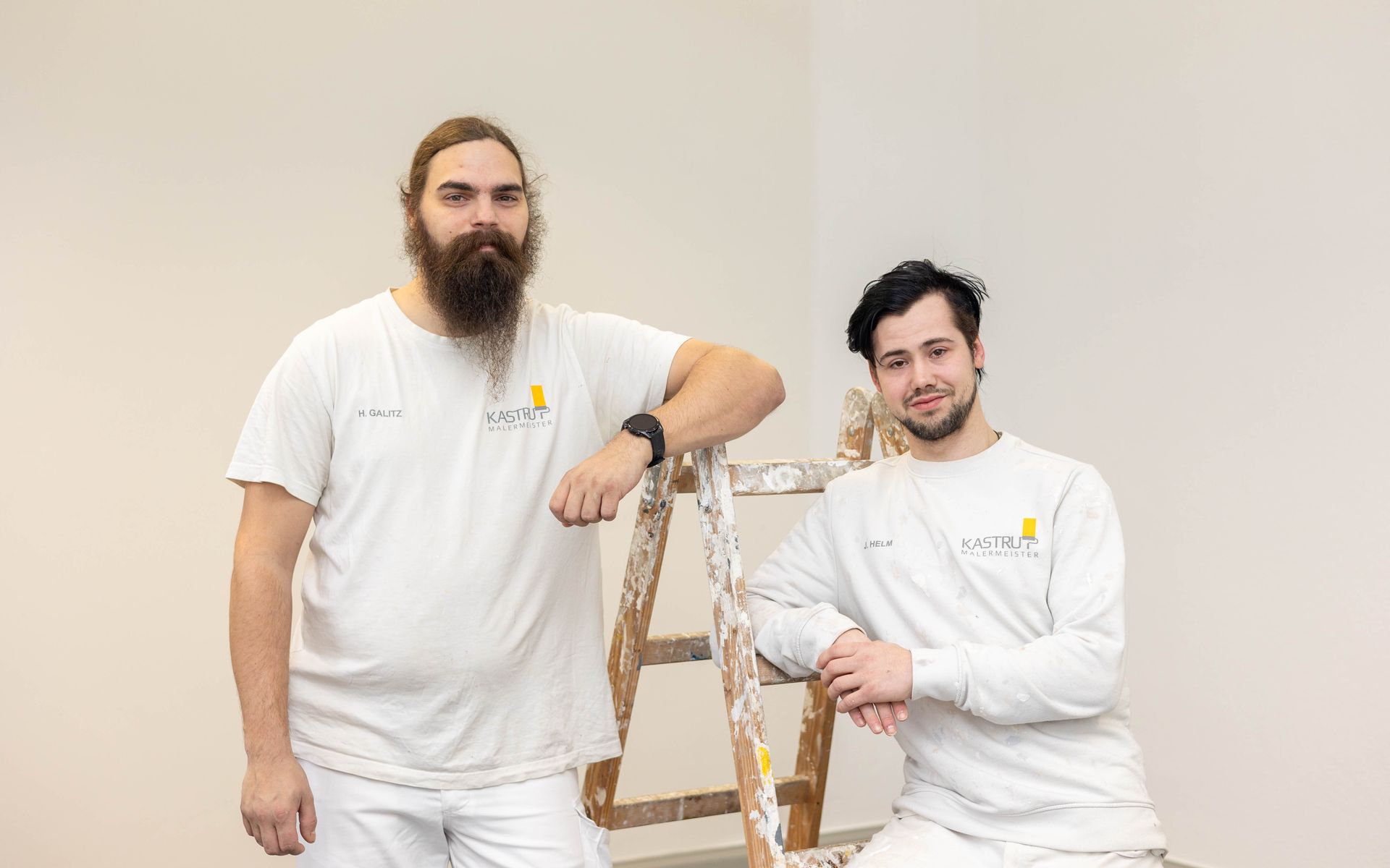 Zwei Männer stehen nebeneinander vor einer Wand.
