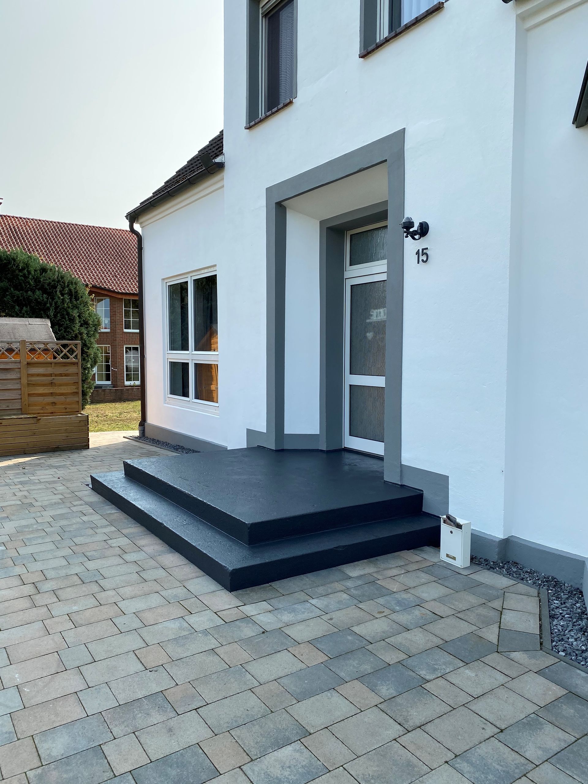 Ein weißes Haus mit einer schwarzen Veranda und Stufen