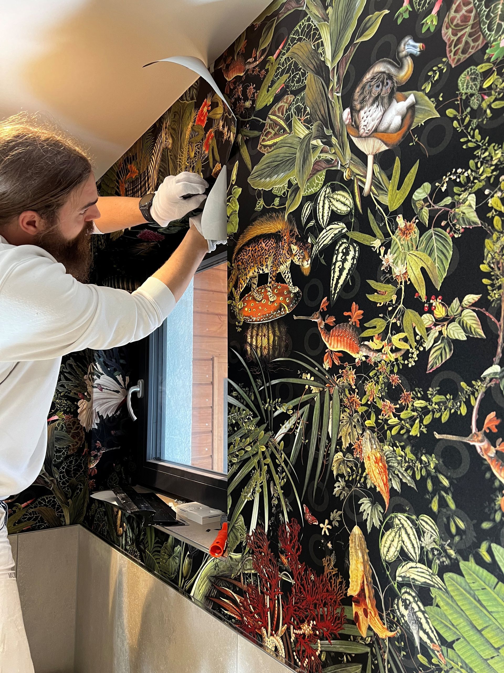 Ein Mann bringt eine Tapete an einer Wand an.