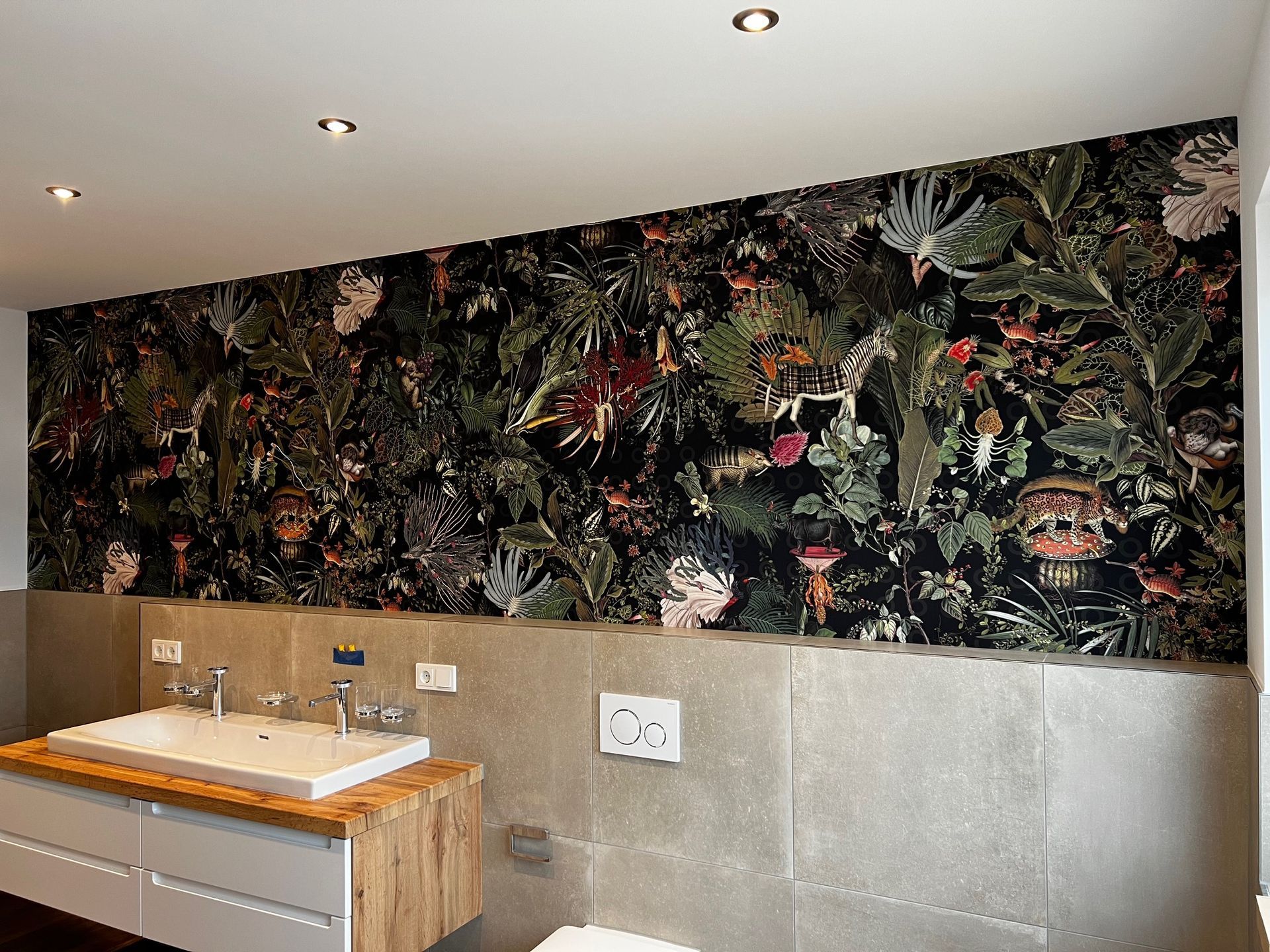 Ein Badezimmer mit Waschbecken, Toilette und einer großen Blumentapete an der Wand.