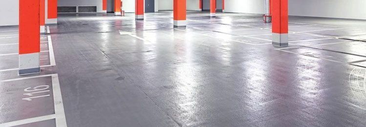 Un piso de concreto en un estacionamiento con pilares naranjas.