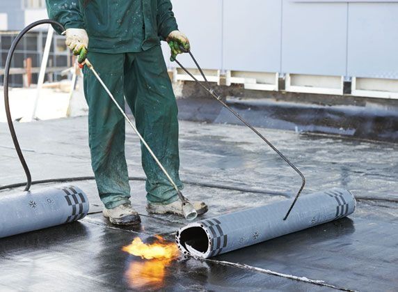 Un hombre está trabajando en un tejado con una antorcha.