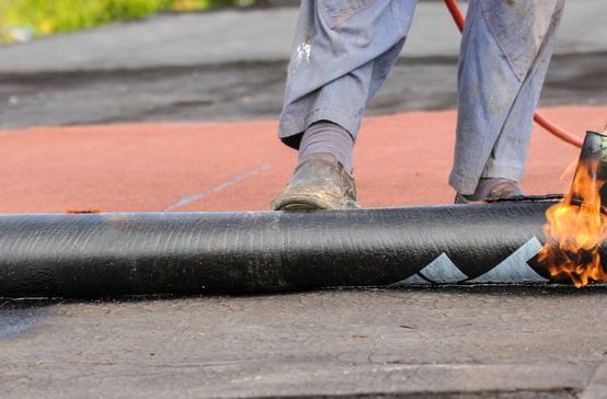 Una persona está colocando un rollo de asfalto en el suelo.