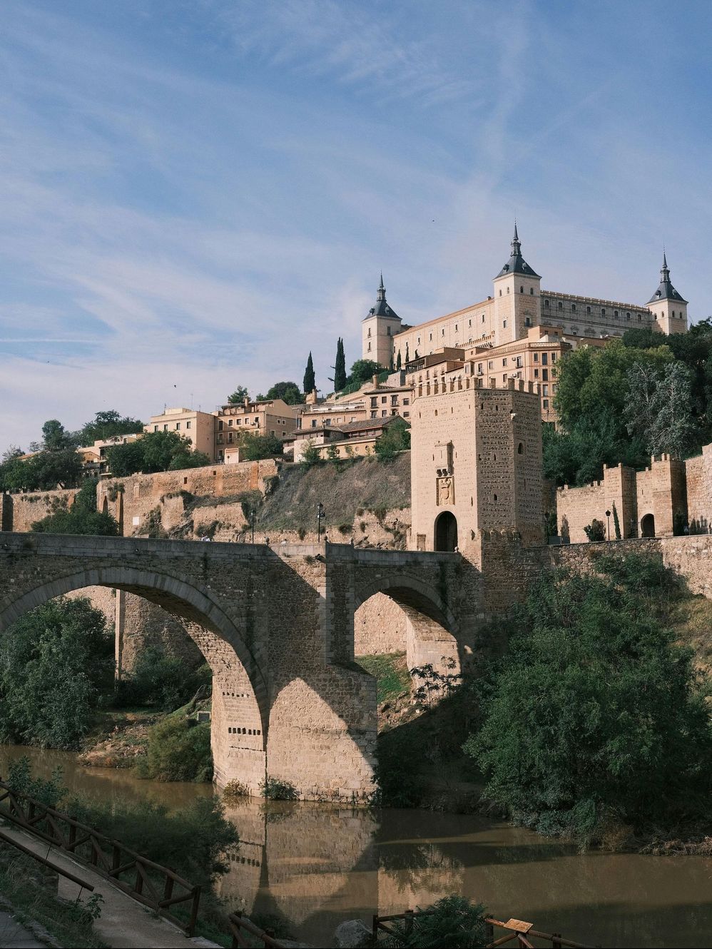 Un puente sobre un río con un castillo al fondo