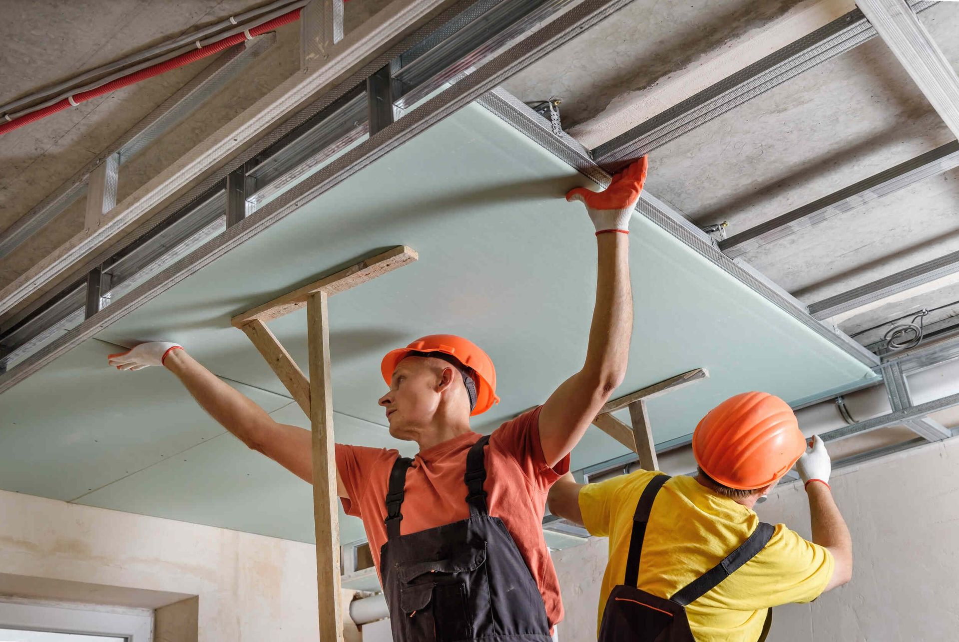 Dos hombres están trabajando en el techo de una habitación.