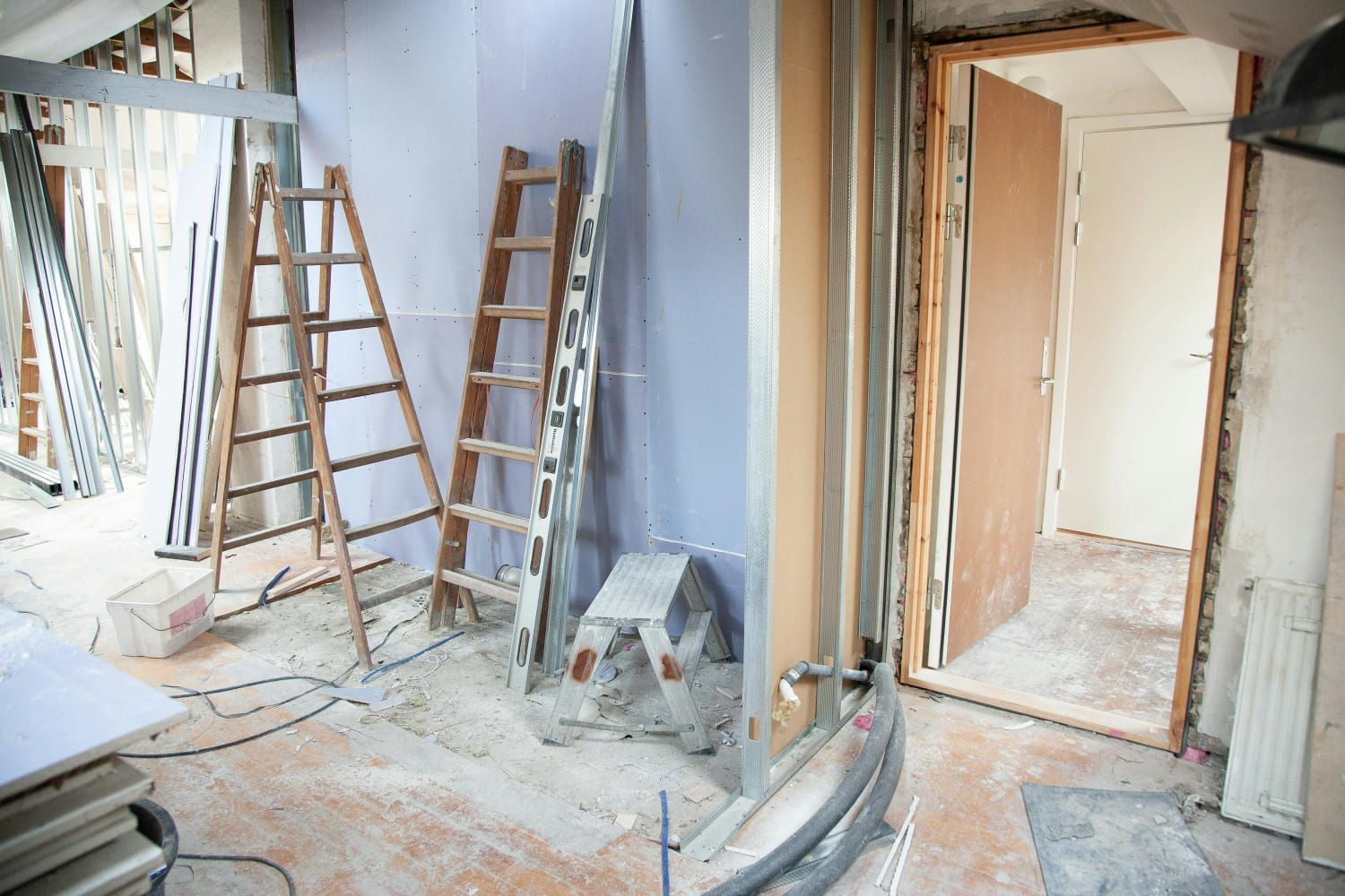 Una habitación en construcción con una escalera y un taburete en el suelo.