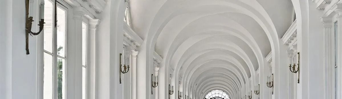 Couloir blanc voûté avec colonnes ornementées et appliques murales suspendues