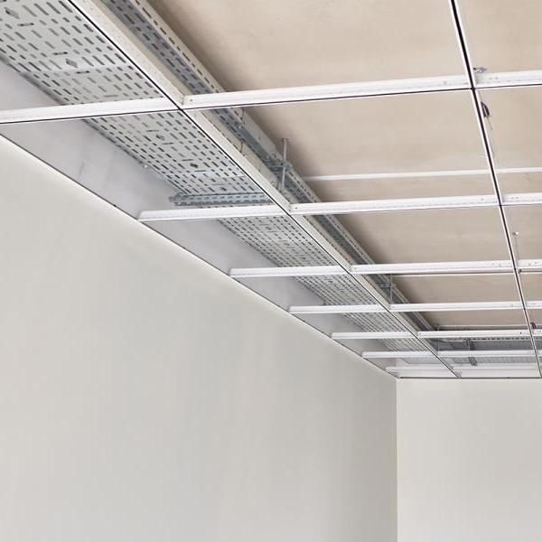 Plafond blanc avec chemins de câbles métalliques apparents et poutres de soutien au-dessus de murs nus