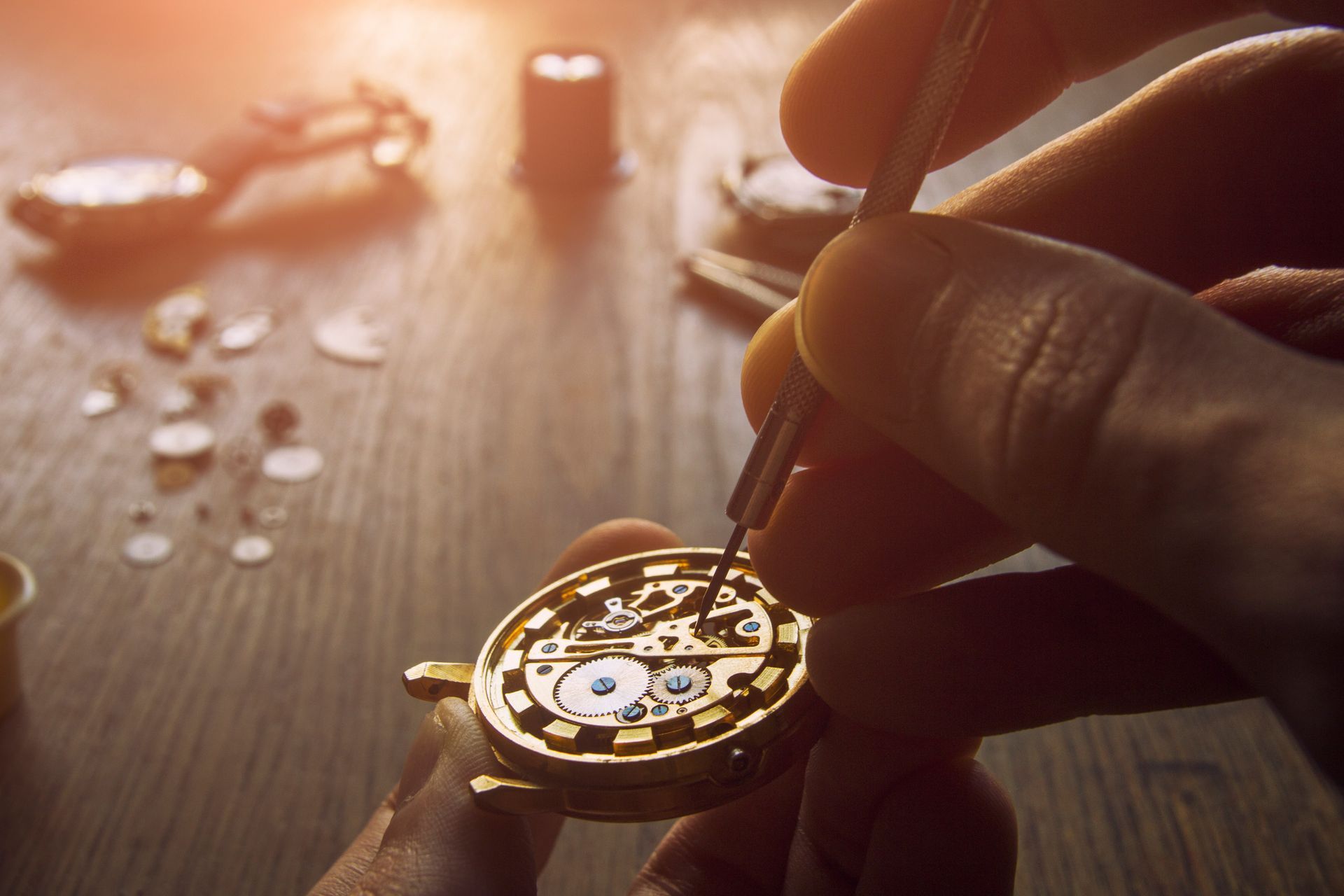 Una persona está arreglando un reloj en una mesa de madera.