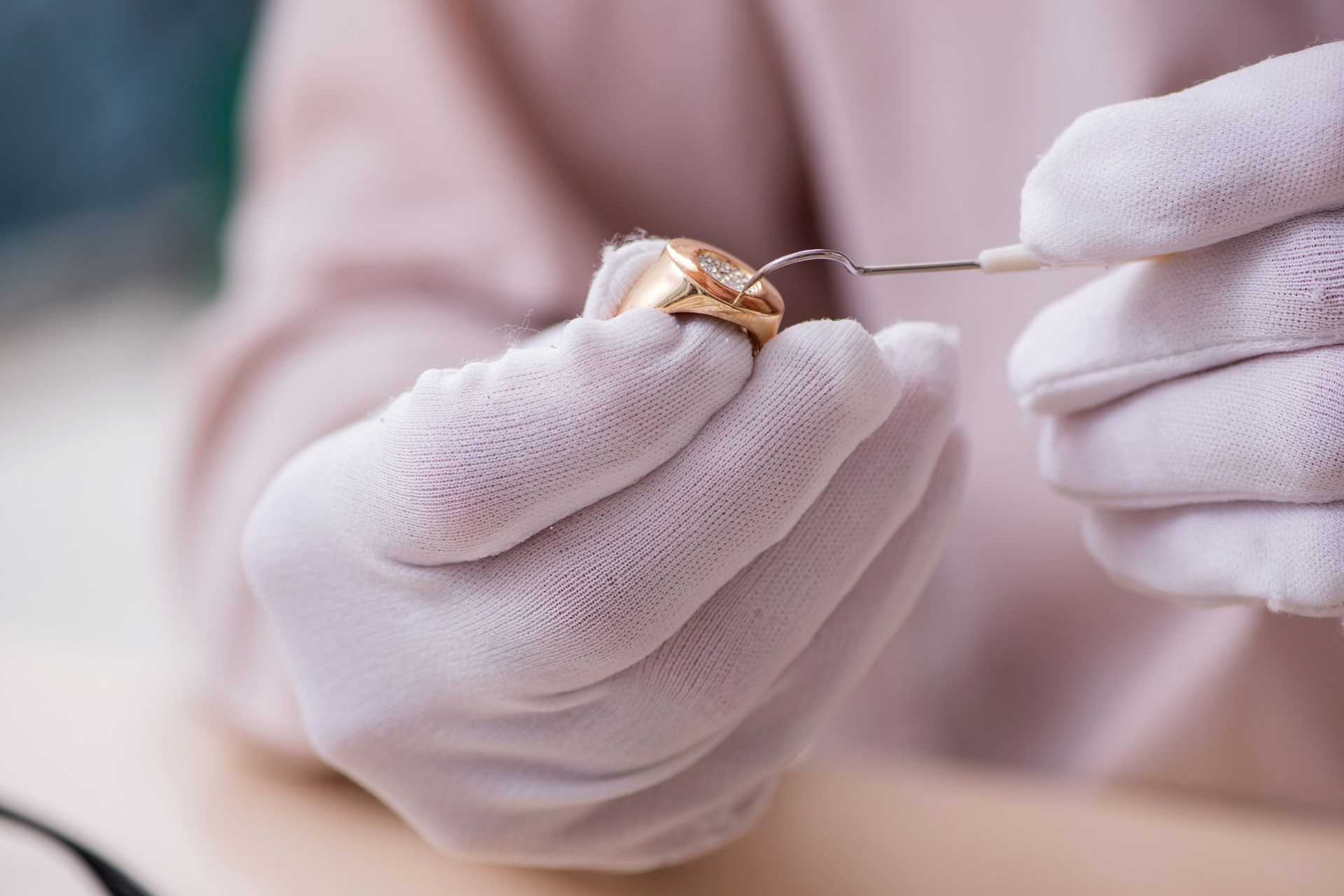 Una persona que lleva guantes blancos sostiene un anillo de oro.