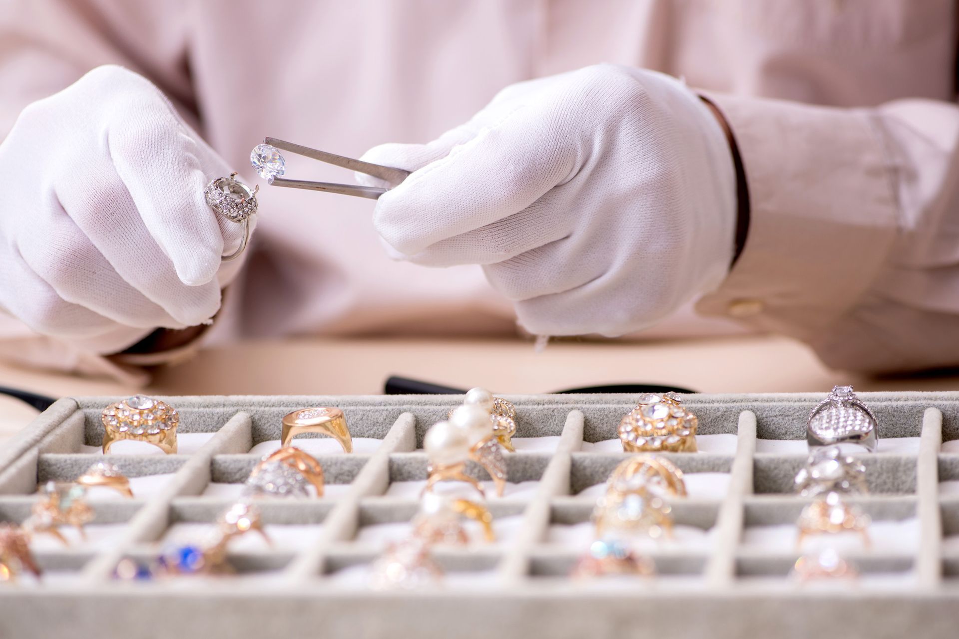 Una persona sostiene un diamante delante de una bandeja de anillos.