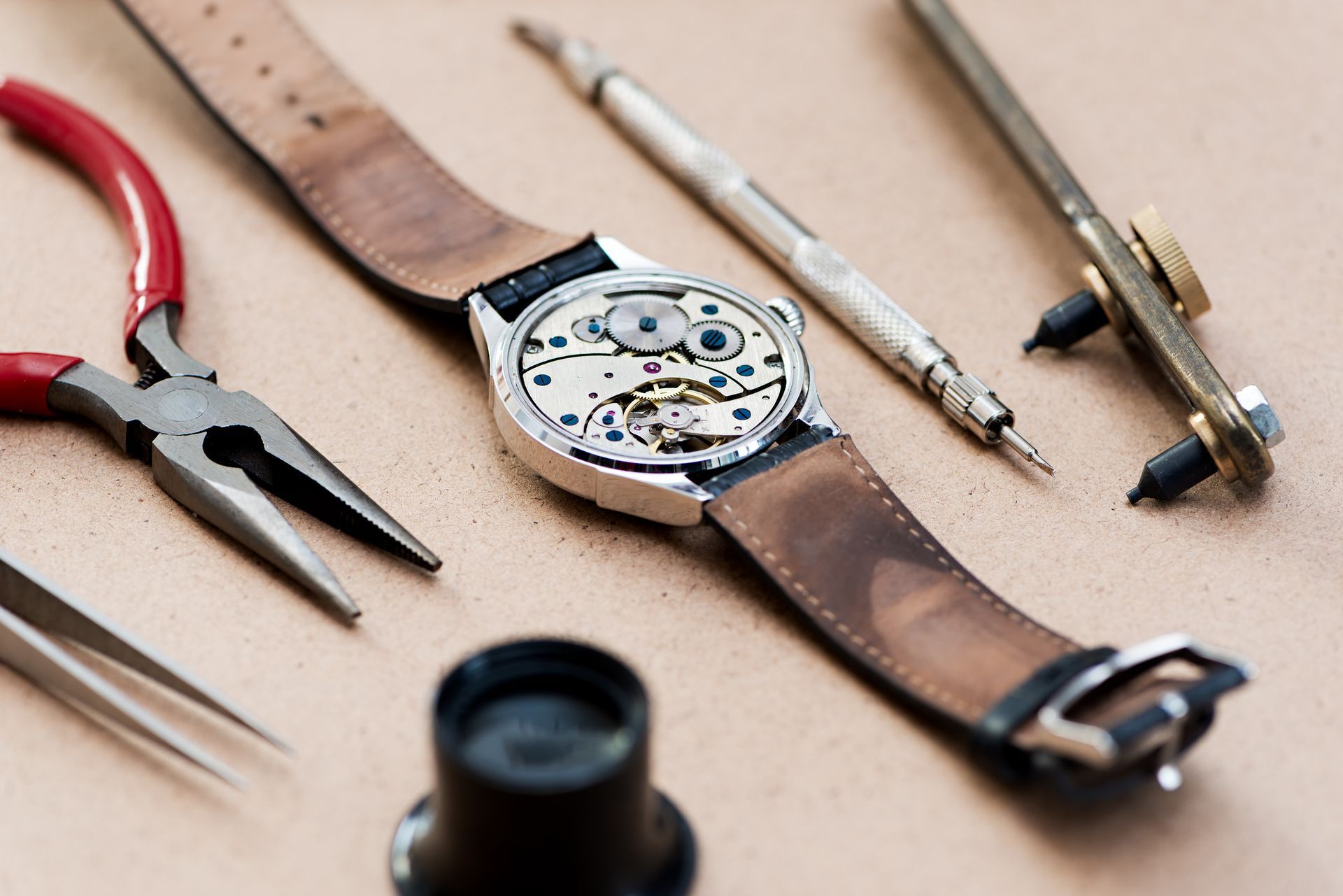 Se está reparando un reloj con herramientas sobre una mesa.