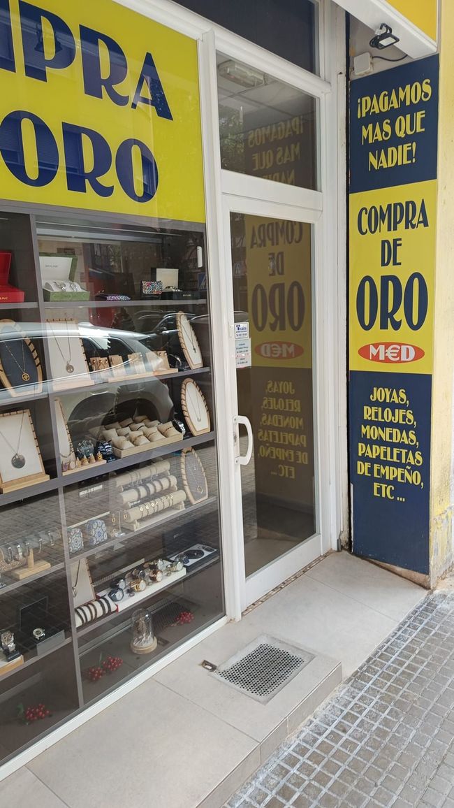 Un escaparate con un cartel amarillo que dice compra de oro