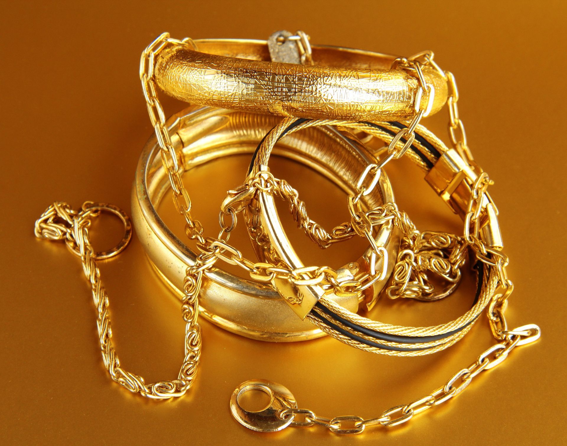 Una pila de joyas de oro, incluyendo pulseras y cadenas.