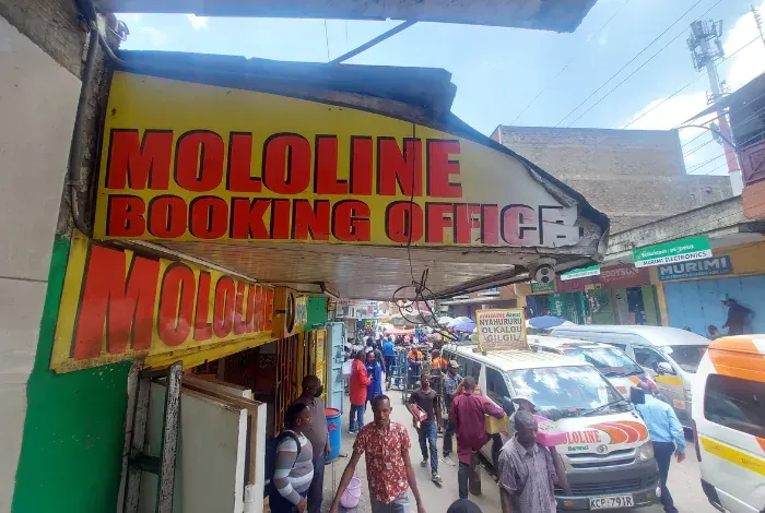 A group of people are walking down a street under a sign that says mololine booking office.