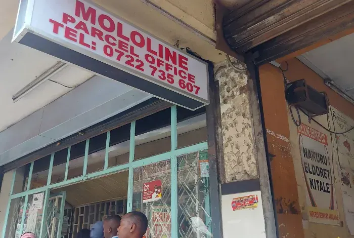 A group of people are standing outside of a mololine parcel office