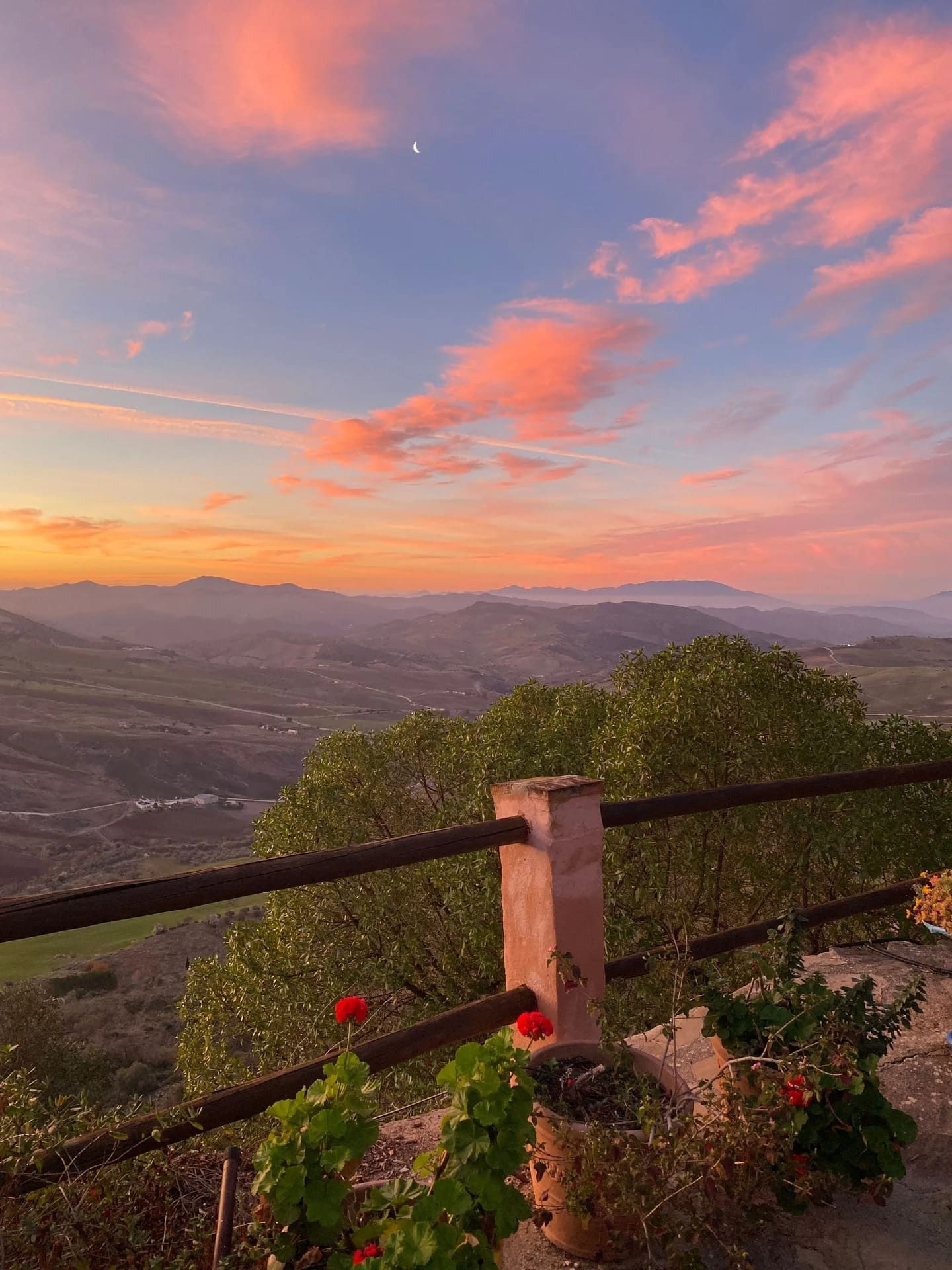 Jacuzzi en patio con vista a colinas verdes, barandilla de madera, día soleado.