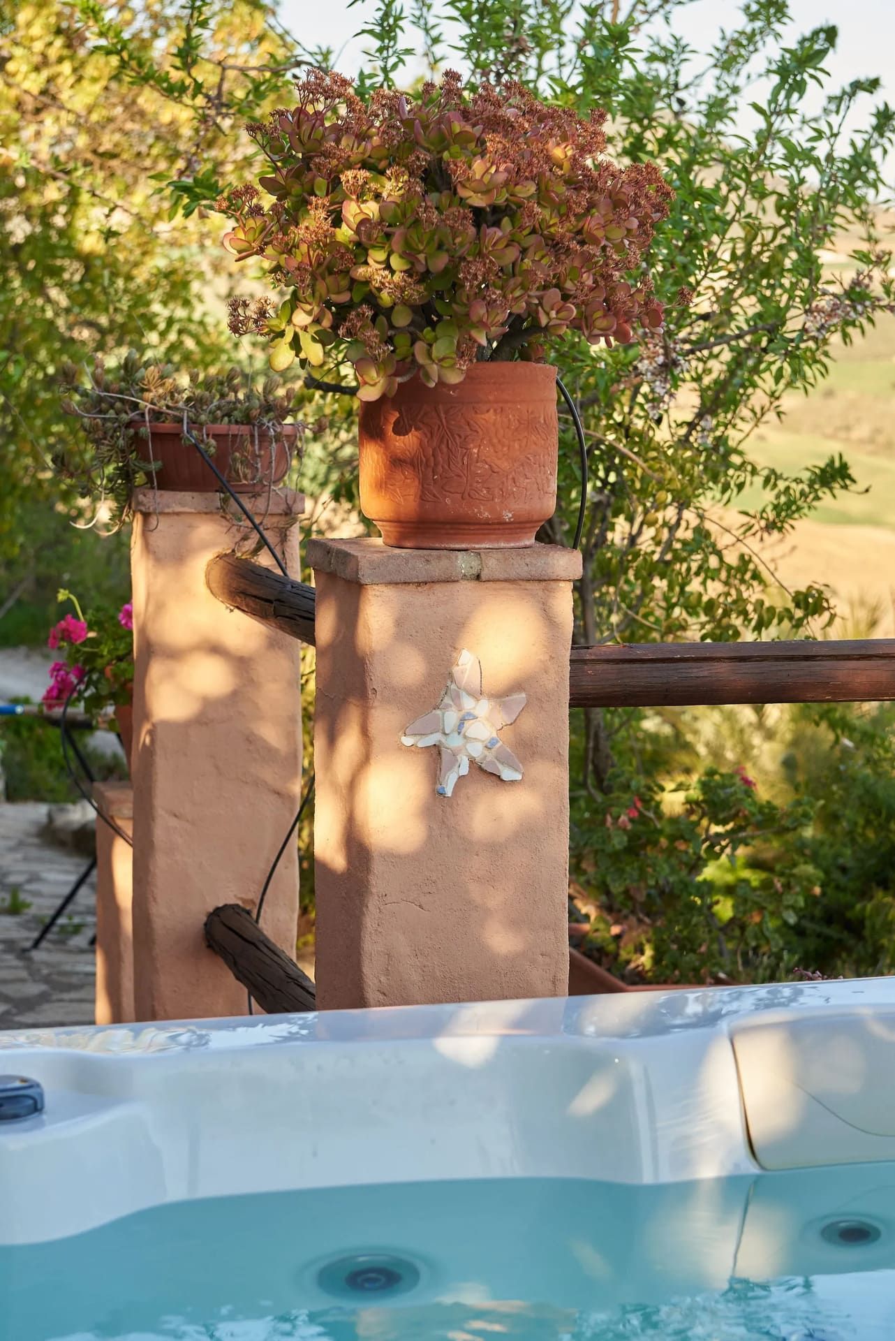 El jacuzzi tiene vistas al campo con un poste decorativo que sostiene una planta en maceta.