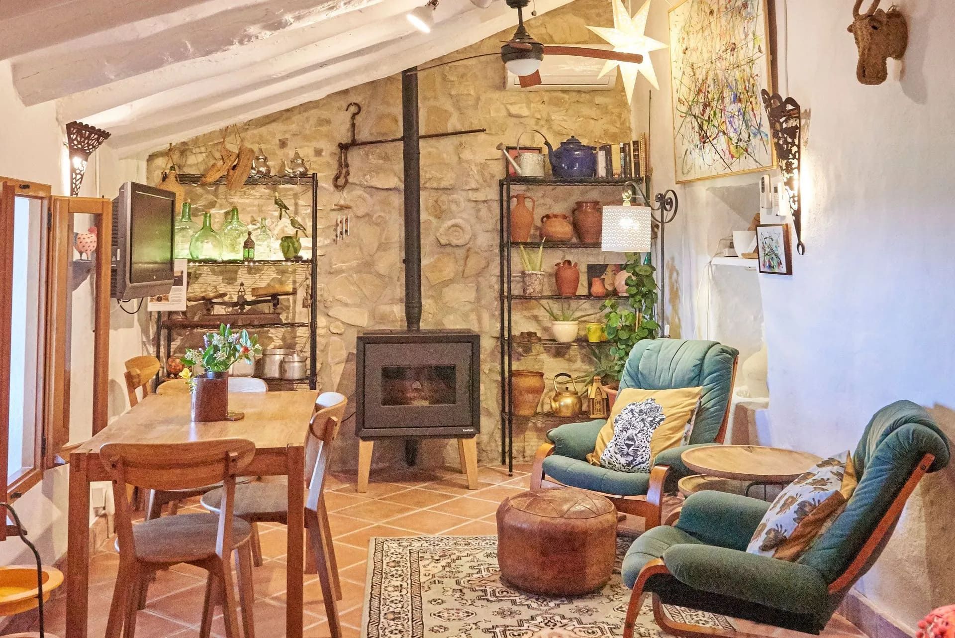 Baño con azulejos de piedra, espejo arqueado, estatuas y estantes decorativos con cerámica.