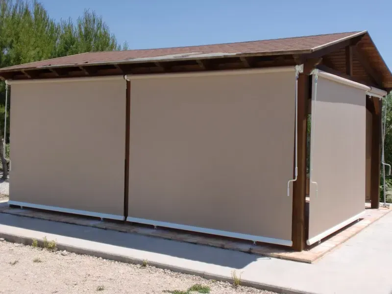 Un cobertizo con techo marrón y persianas beige en el lateral.
