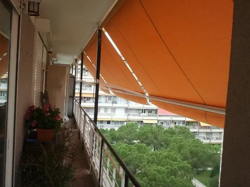 Un balcón con un toldo naranja encima.