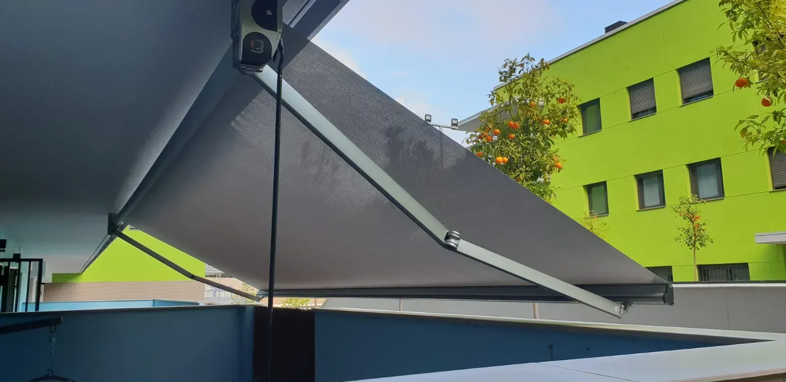 Un gran toldo cuelga del techo de un edificio frente a un edificio verde.