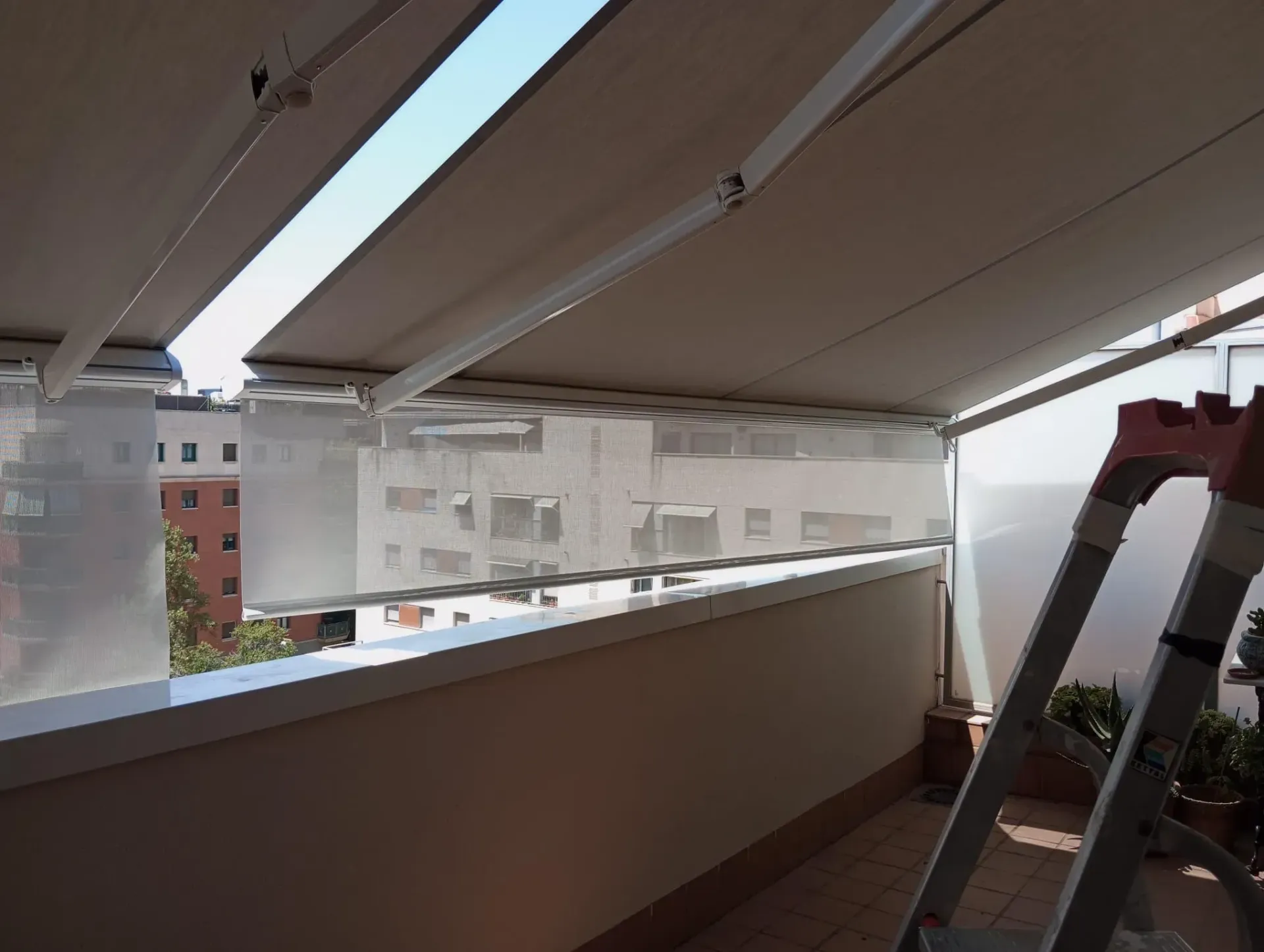 Un balcón con un toldo blanco y una escalera.
