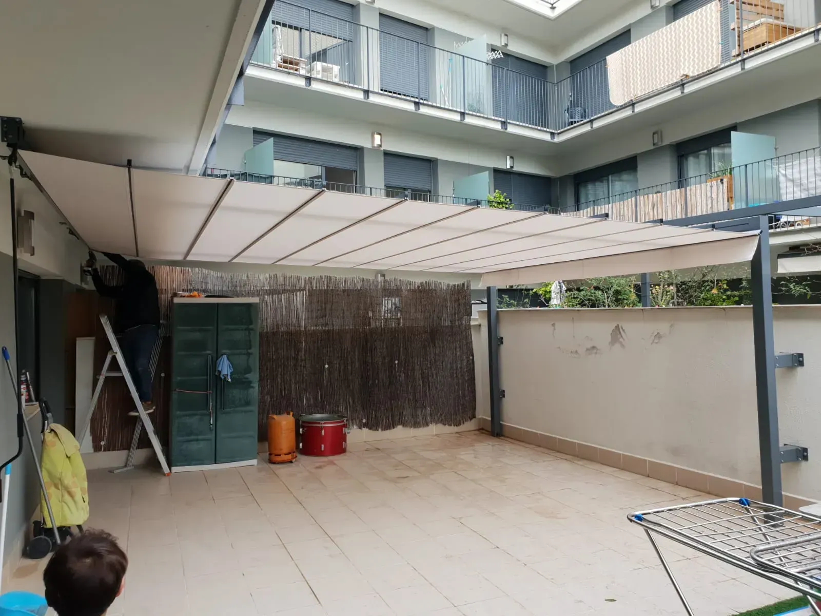 Un hombre está de pie bajo un dosel en un patio.