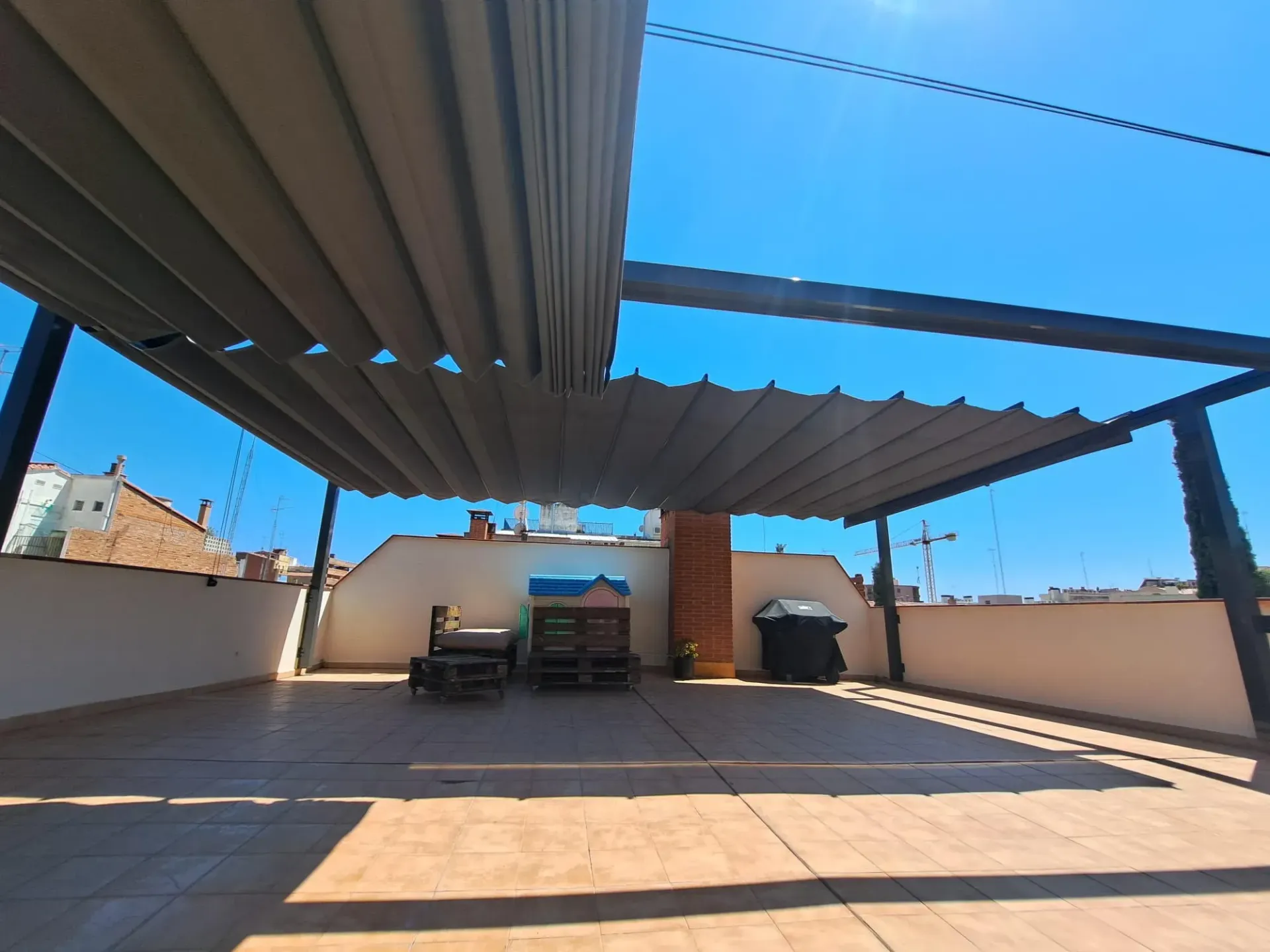 Un patio en la azotea con un dosel encima