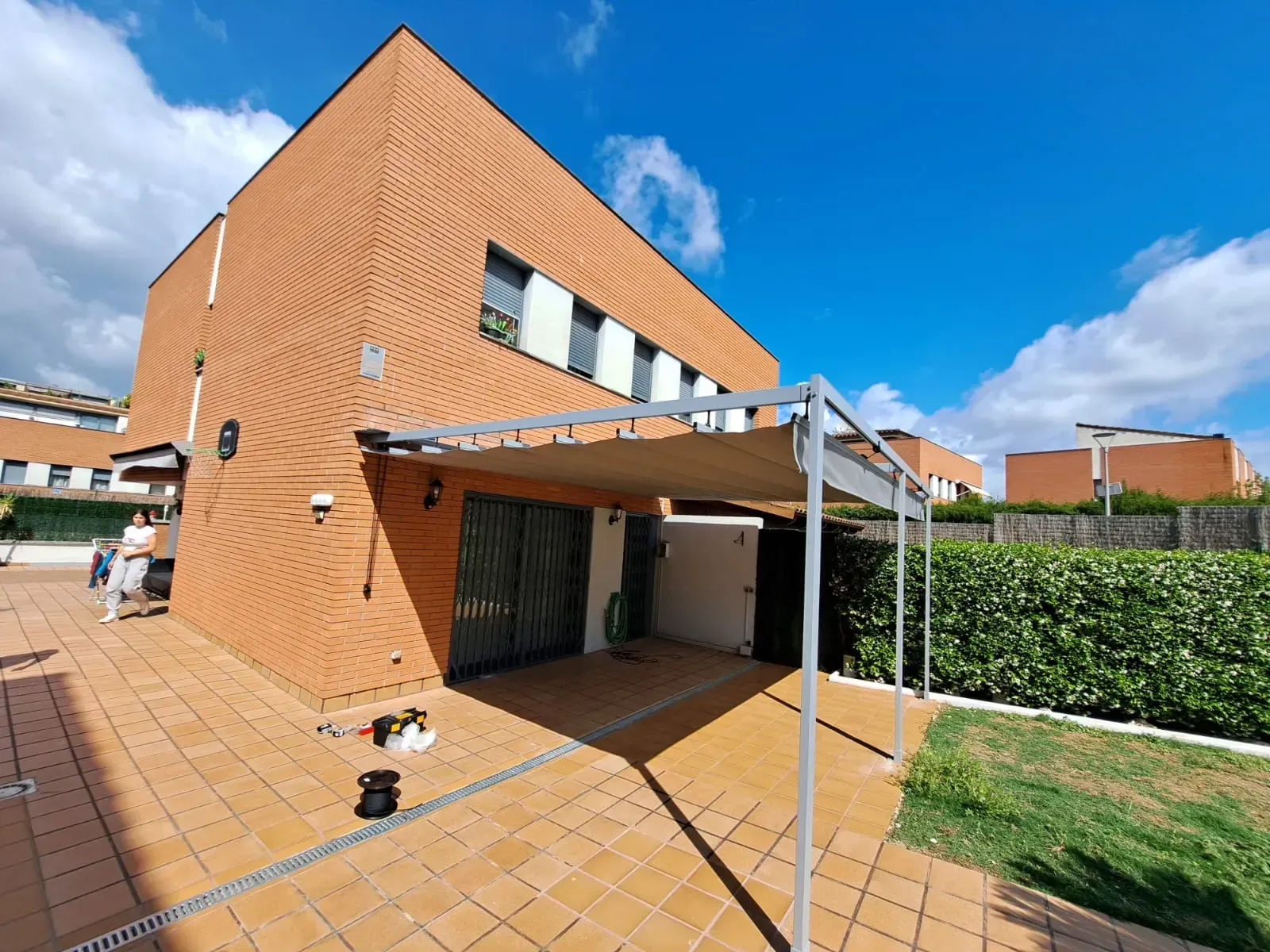Una casa de ladrillo con una pérgola delante.