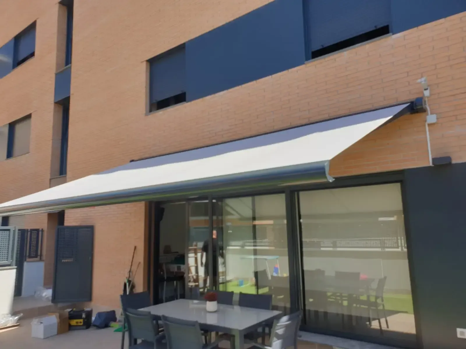 Un patio con una mesa y sillas bajo un toldo.