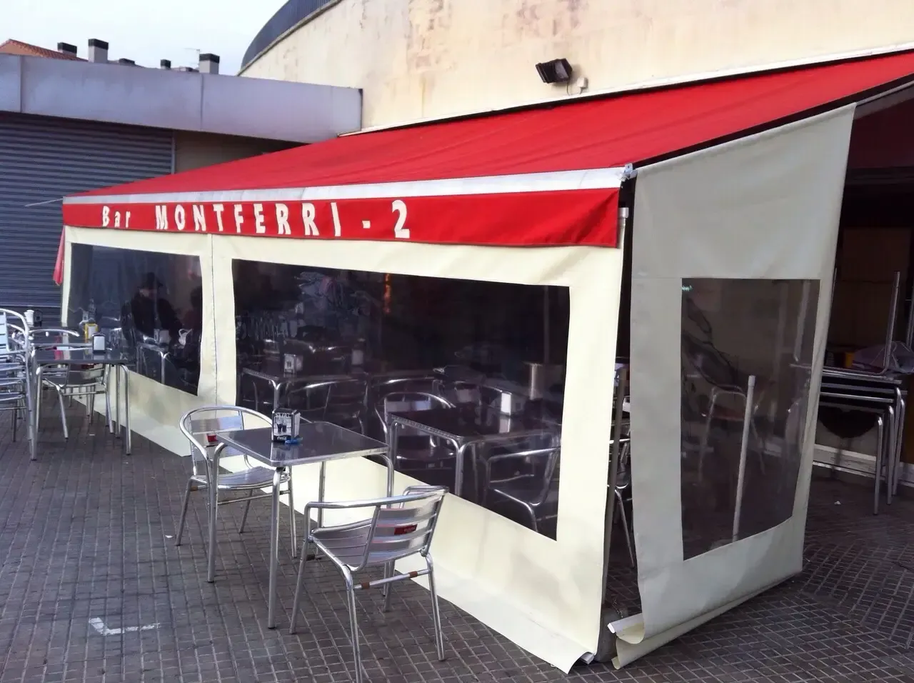 Un restaurante con mesas y sillas bajo un toldo que dice bar montferri 2