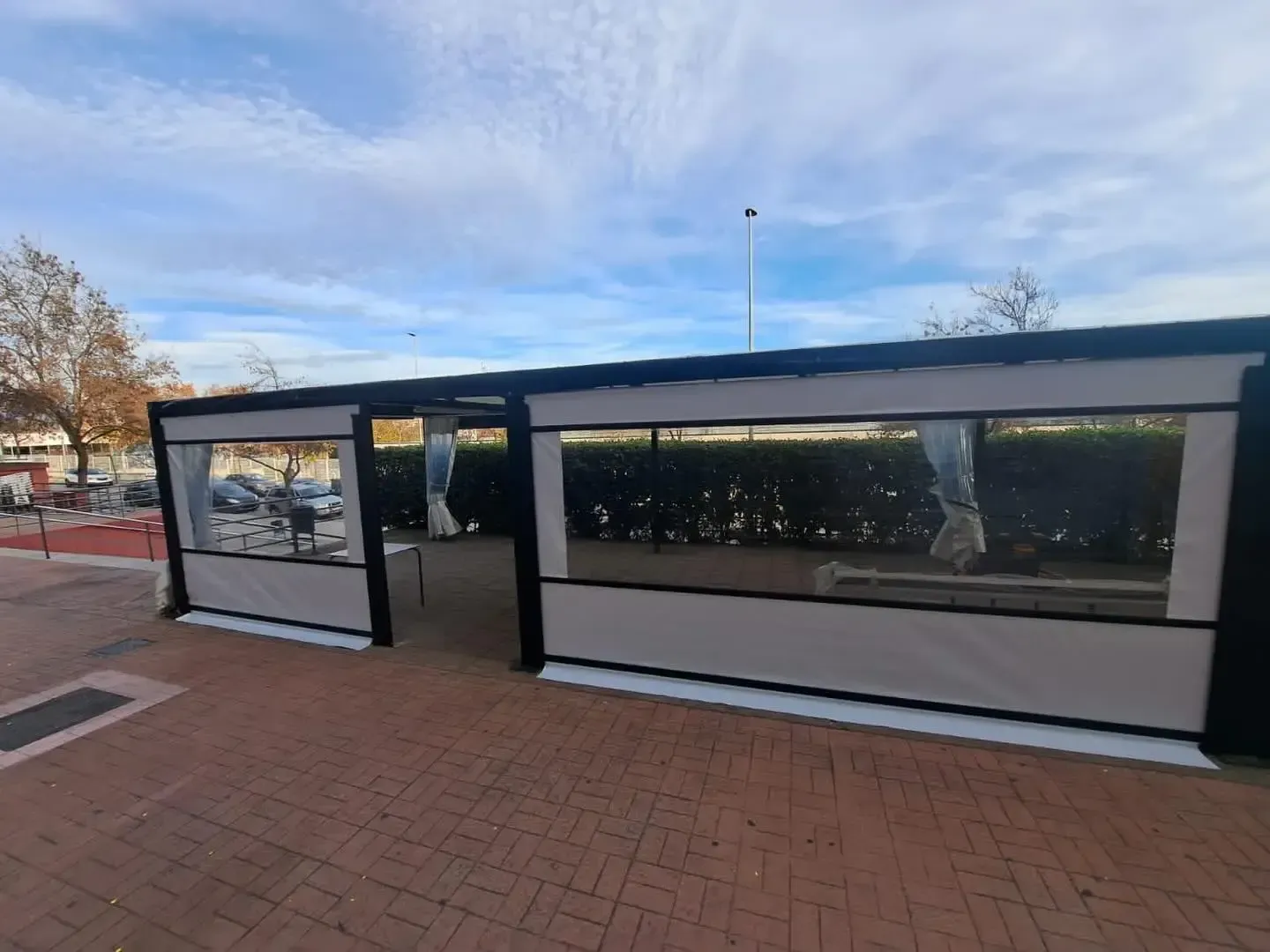 Un edificio con muchas ventanas está sentado sobre una acera de ladrillos.