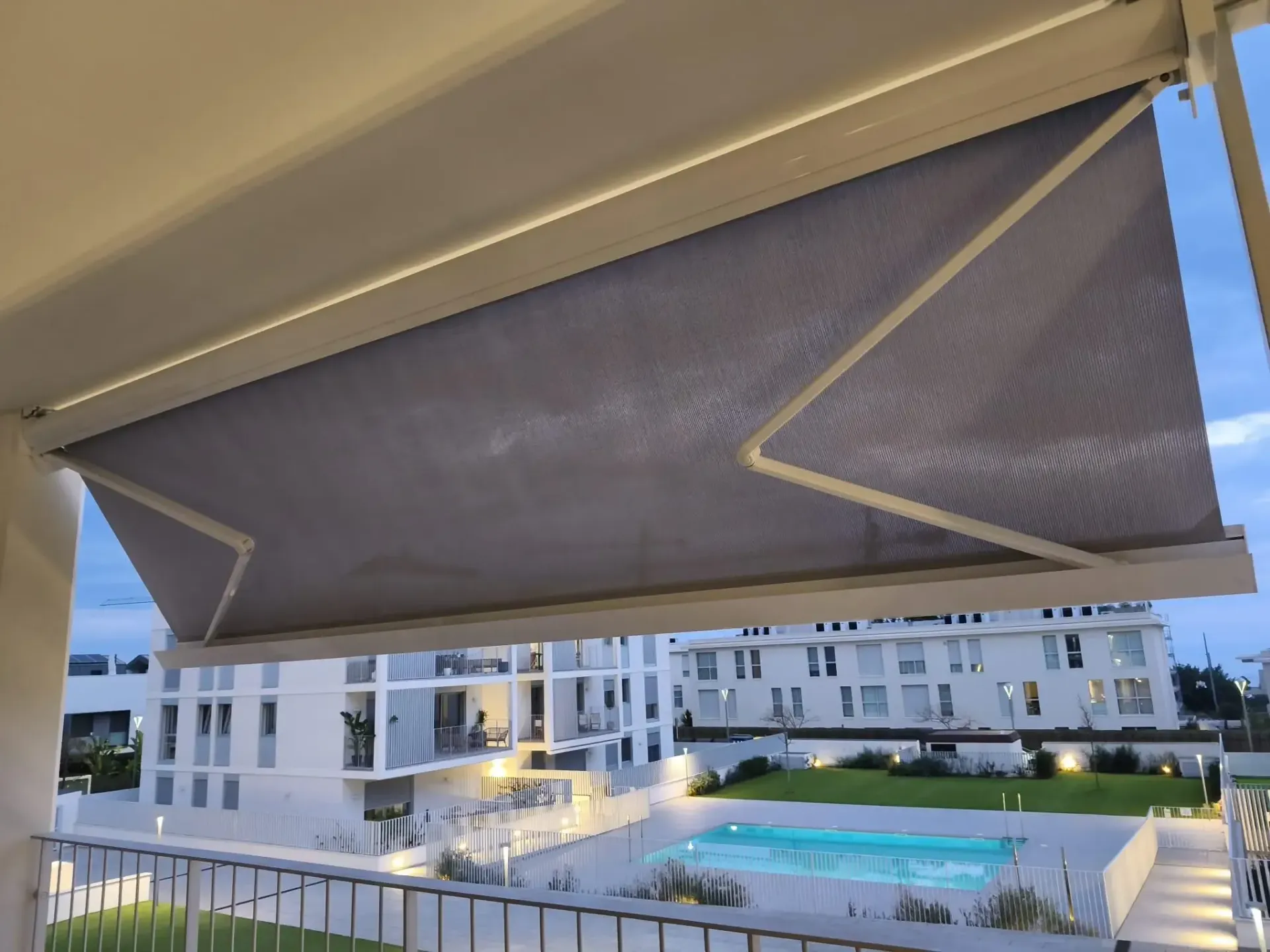 Un balcón con un toldo encima y una piscina al fondo.