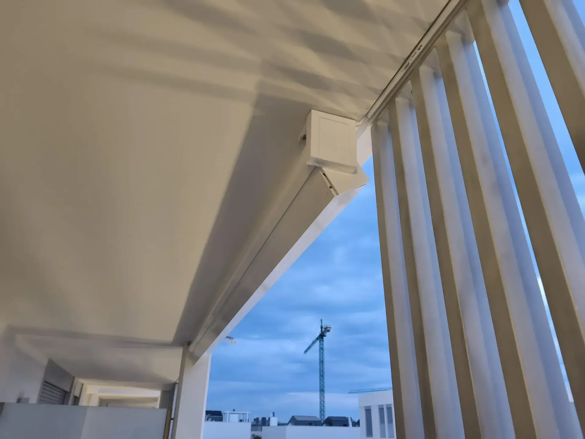 Un toldo blanco cuelga del techo de un balcón.