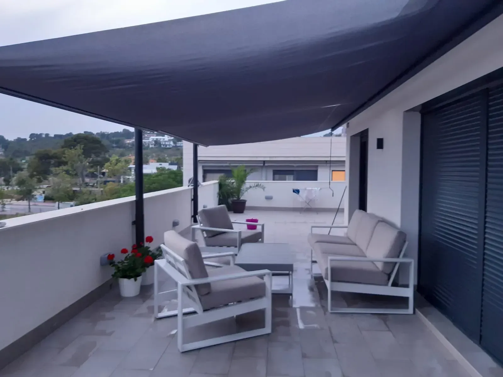 Un balcón con un sofá y sillas bajo un toldo.