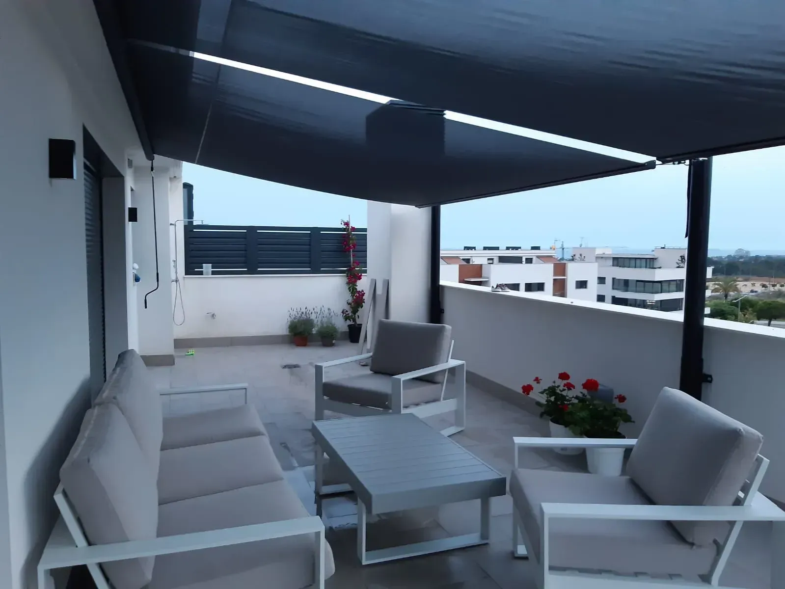 Un balcón con un sofá y sillas bajo un toldo.